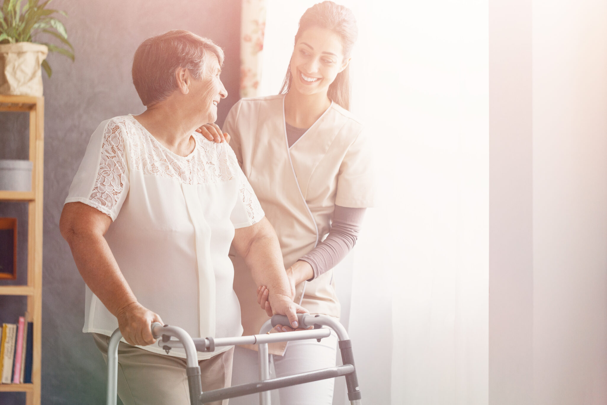 A long term care nurse helps a senior woman use a walker