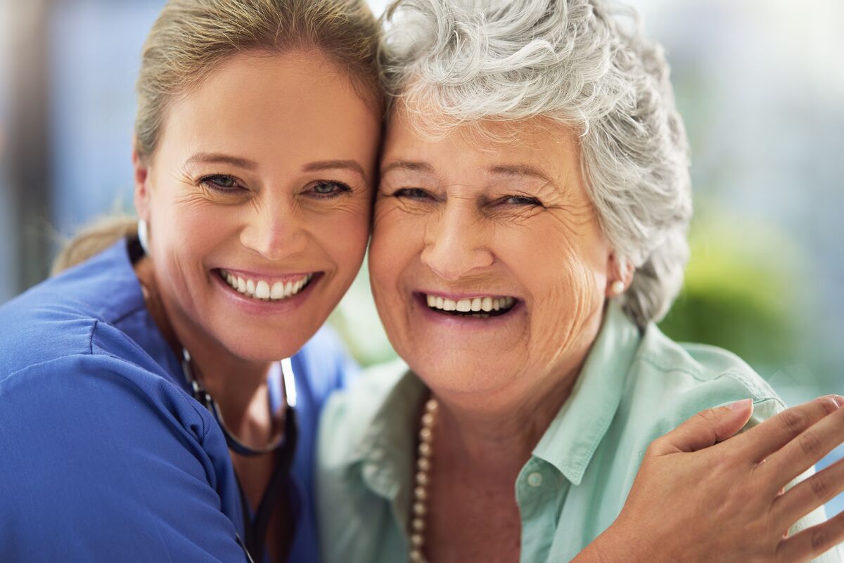 Senior woman hugging and smiling with nurse